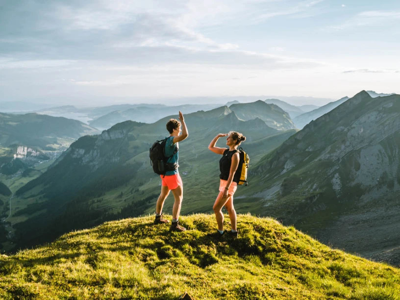 Zwei Personen stehen auf einem Berg und geben sich High Five